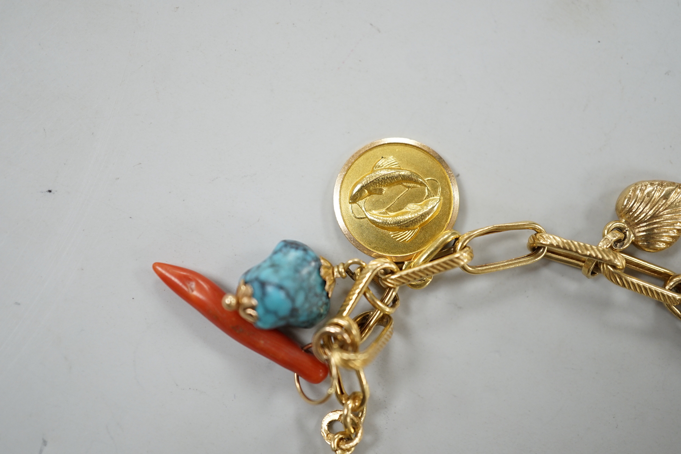 A modern Italian yellow metal charm bracelet, hung with eleven assorted charms, including 750 and enamel jockey cap, agate clasped hand and 750 acorn